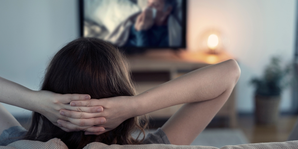 adult watching a movie on a large tv screen