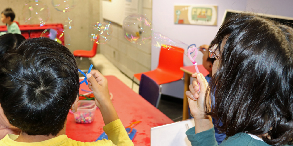two school-age children blowing bubbles during a library program