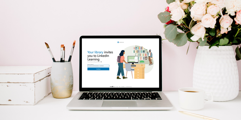 laptop on a desk with linkedin learning resource home page on the screen, vase with flowers and a mug in the background