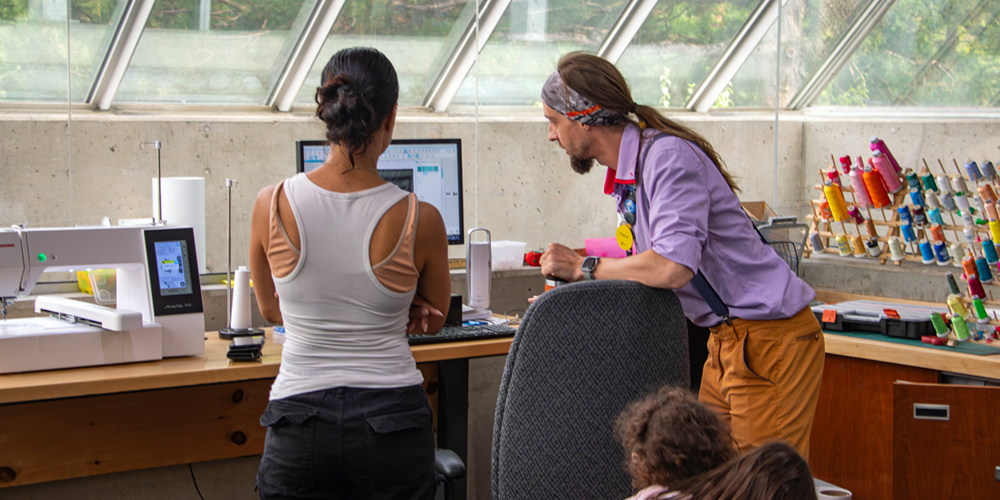MakerSpace staff helping a customer use the embroidery machine.