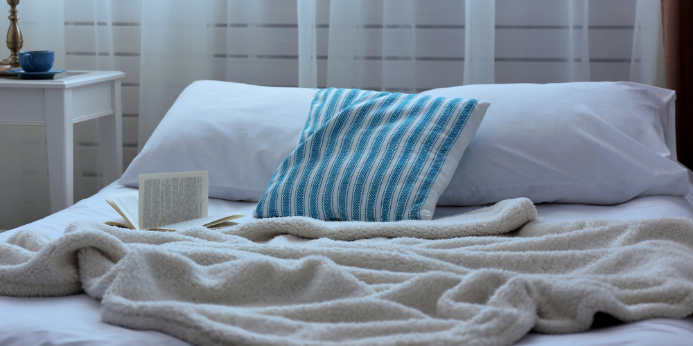 book lying on bed covers with nightstand in background