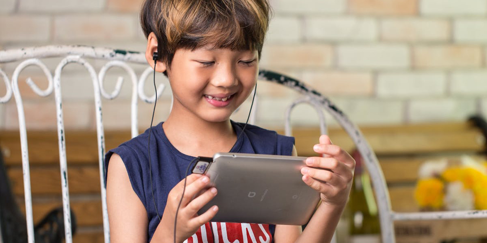 child wearing heaphones looking at a tablet