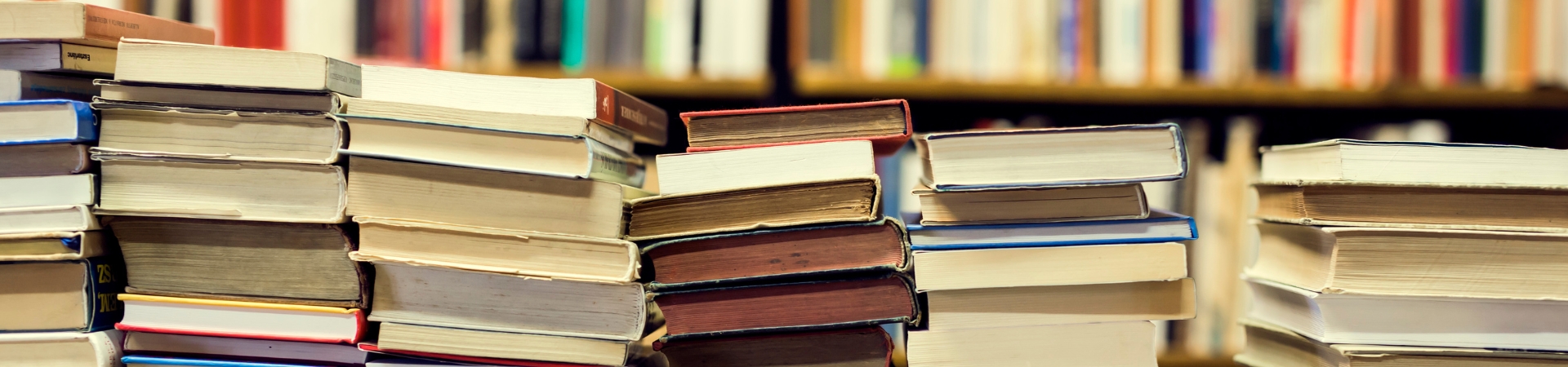 stacks of old books on a table and shelves