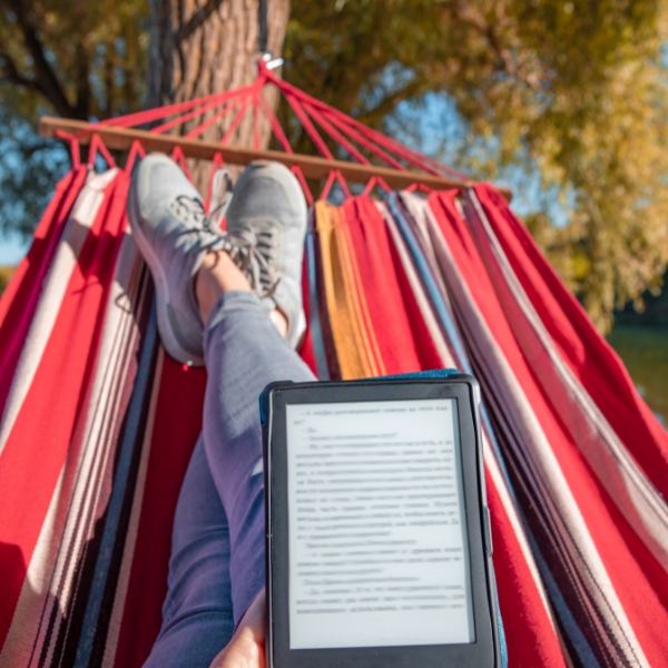 person on a hammock holding a digital book