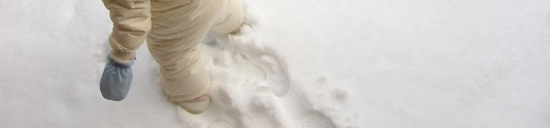 child walking in snow wearing winter clothes